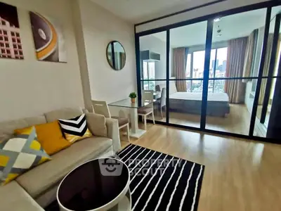 Modern living room with stylish decor and view into cozy bedroom through glass doors.