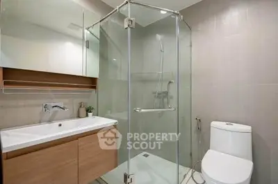 Modern bathroom with glass shower and sleek vanity in contemporary apartment.
