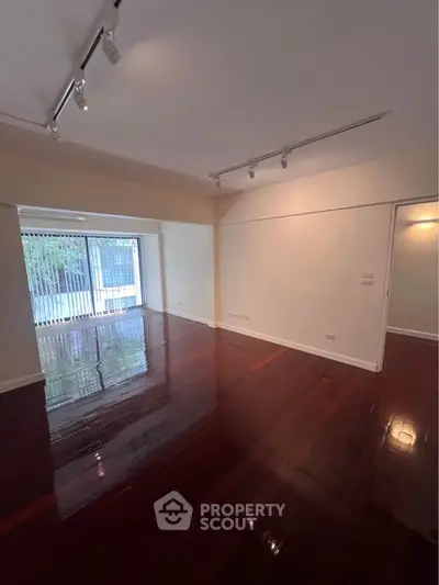 Spacious living room with polished wooden floors and large windows for natural light.