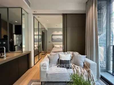 Chic modern living room seamlessly connected to a sleek kitchen, featuring plush sofa, elegant decor, and abundant natural light.