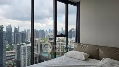Luxurious bedroom with stunning city skyline view through floor-to-ceiling windows.