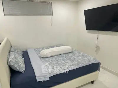 Cozy bedroom with modern decor and wall-mounted TV, perfect for relaxation.