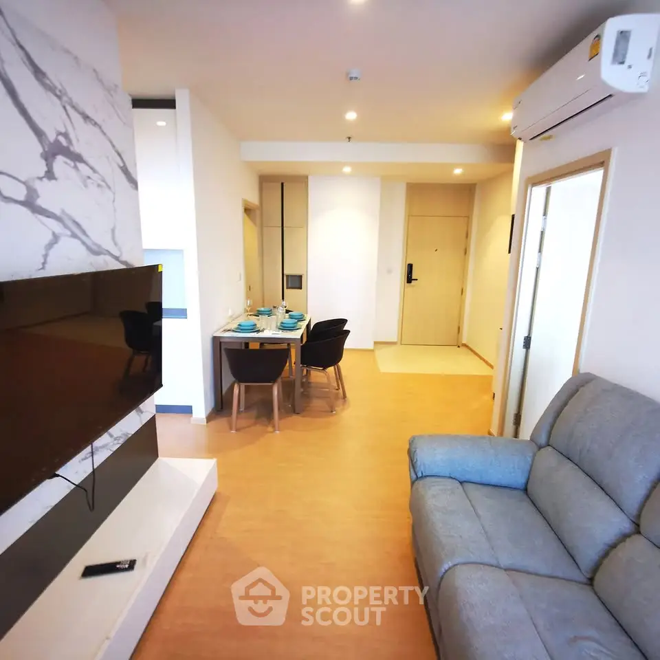 Modern living room with stylish decor, featuring a wall-mounted TV and cozy seating area.