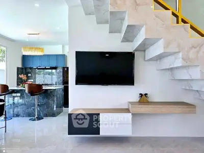 Modern living room with stylish staircase and sleek kitchen in open layout design.