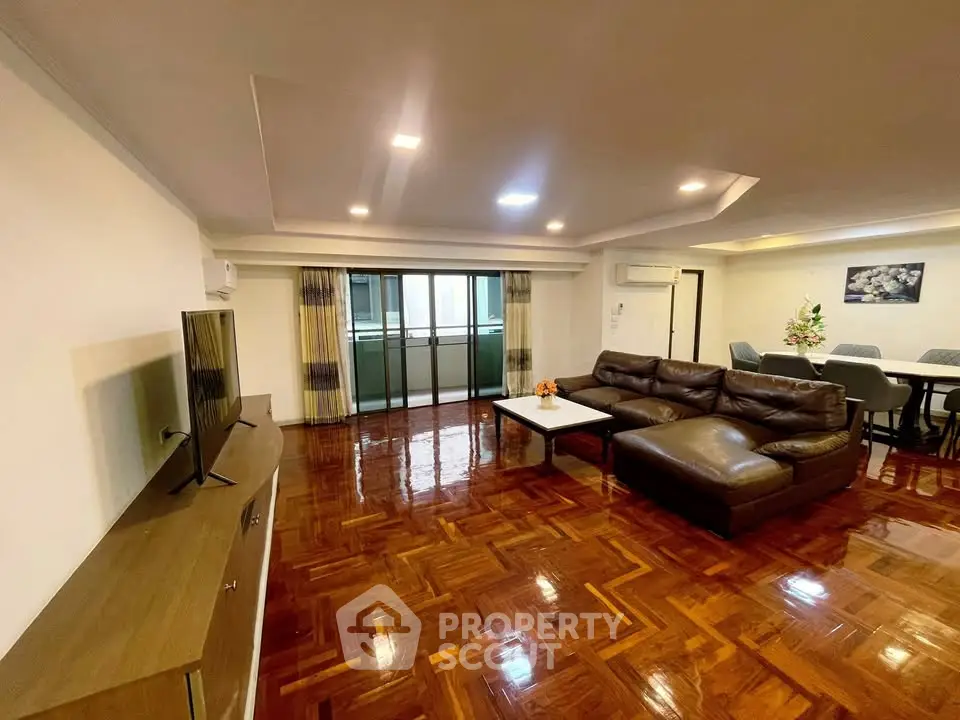 Spacious living room with polished wooden floors and modern furniture in a luxurious apartment.