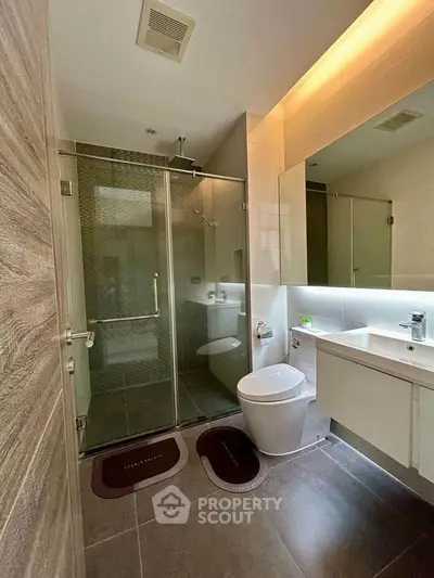 Modern bathroom with glass shower and sleek fixtures in contemporary home.