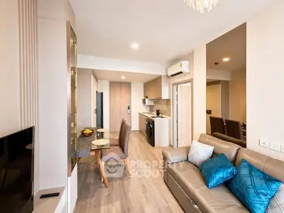 Modern living room with open kitchen, stylish decor, and cozy seating area in a contemporary apartment.