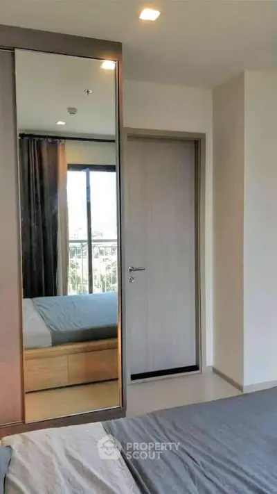Modern bedroom with large mirror and natural light from window