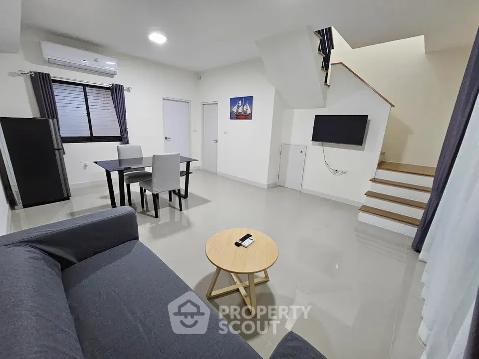 Modern living room with sleek furniture and staircase in a contemporary home.