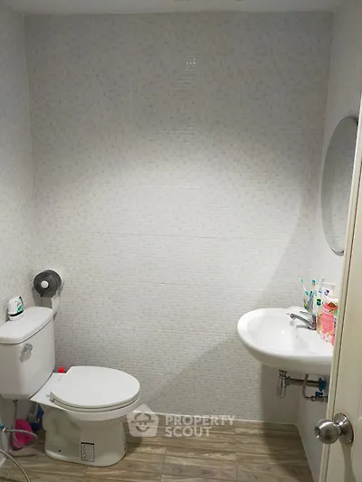 Modern bathroom with white fixtures and tiled walls, featuring a sleek sink and toilet.