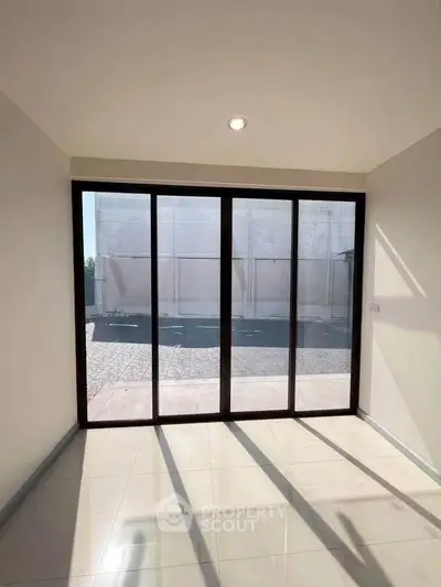 Spacious room with large glass doors offering ample natural light and outdoor view.