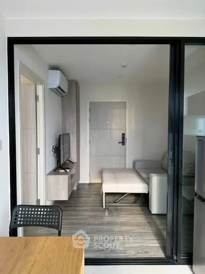 Modern living room with sleek furniture and air conditioning, featuring a cozy sofa and wall-mounted TV.