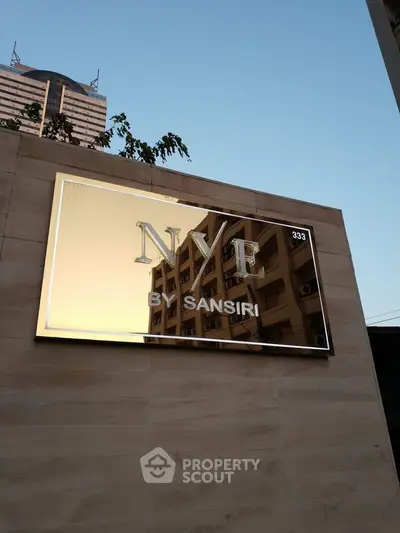 Modern building exterior with reflective sign displaying NYE by Sansiri.