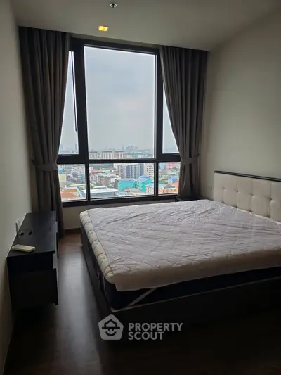 Modern bedroom with large window offering cityscape view, featuring a comfortable bed and sleek design.