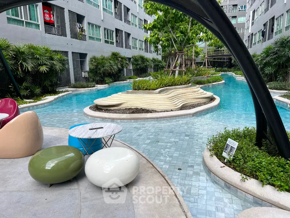 Luxurious apartment complex with stunning pool and modern outdoor seating area.