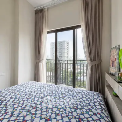 Cozy bedroom with large window offering city view, featuring modern decor and natural light.