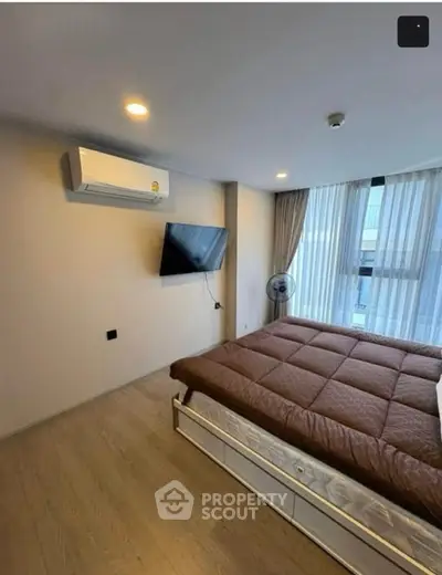 Modern bedroom with large window, air conditioning, and wall-mounted TV in a stylish apartment.