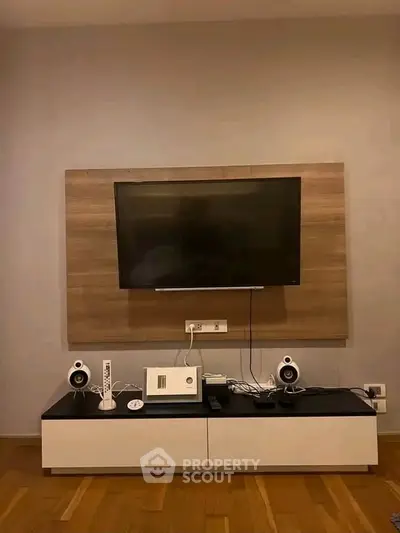 Modern living room with wall-mounted TV and sleek entertainment unit.