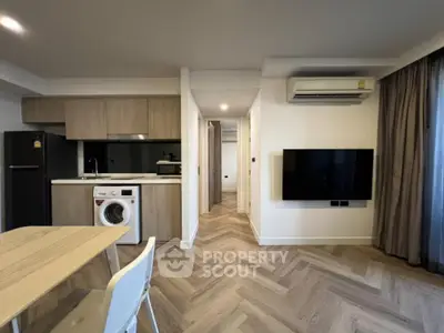Modern apartment interior with kitchen and living area featuring wooden flooring and sleek appliances.
