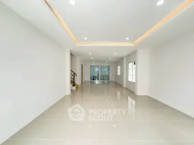 Spacious modern living room with glossy tiled floors and recessed lighting, perfect for family gatherings.