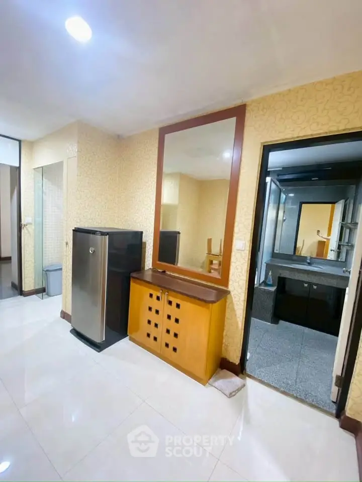 Spacious interior with modern fridge and elegant vanity near bathroom entrance.