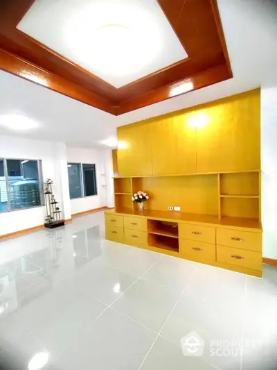 Spacious modern living room with built-in wooden cabinets and glossy tile flooring.