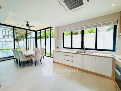 Spacious modern kitchen with dining area and large windows overlooking garden.