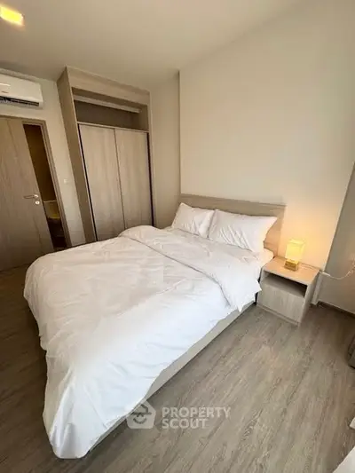 Cozy bedroom with modern design and wooden flooring, featuring a comfortable bed and soft lighting.