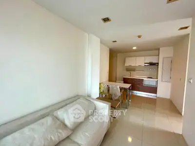 Modern open-layout living room and kitchen with sleek furniture and tiled flooring.