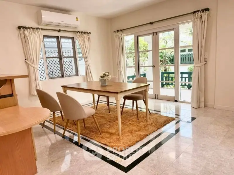 Bright dining area with elegant table and chairs, large windows, and garden view.