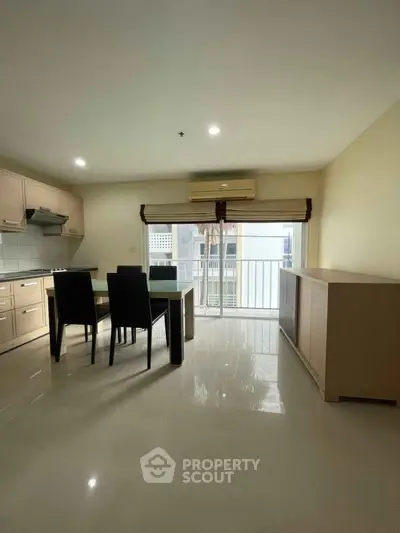 Modern kitchen with open layout and dining area, featuring sleek cabinetry and large windows.