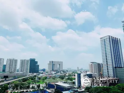 Stunning cityscape view with modern high-rise buildings and lush greenery under a clear blue sky.