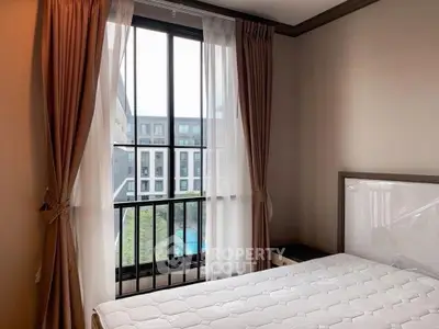 Cozy bedroom with large window offering a stunning view of modern architecture.