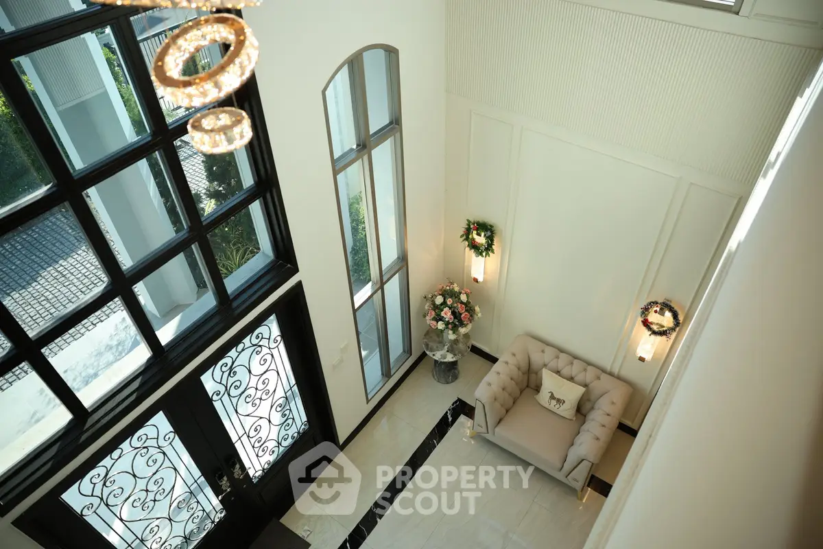 Luxurious entrance with elegant chandelier and plush seating in a modern home