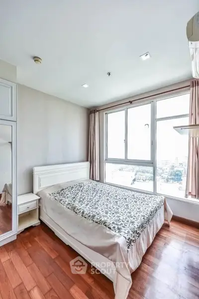 Bright bedroom with large window and wooden flooring in modern apartment