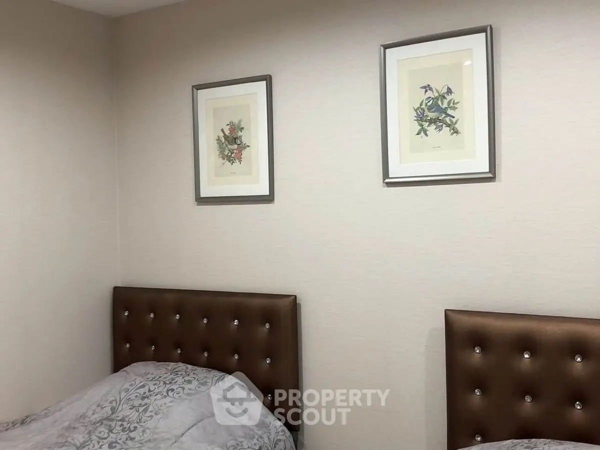 Cozy bedroom with twin beds and elegant framed artwork on the wall.