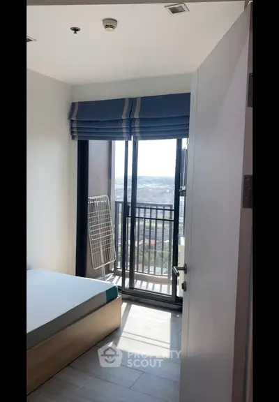 Bright bedroom with balcony and city view, featuring modern decor and ample natural light.