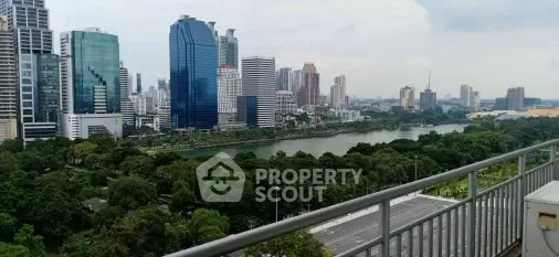 Stunning city skyline view from a high-rise balcony overlooking lush greenery and a serene river.