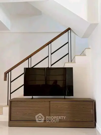 Modern interior with sleek staircase and stylish TV stand in a contemporary living space.