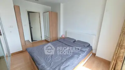 Cozy bedroom with wooden flooring and ample natural light, featuring a comfortable bed and modern wardrobe.
