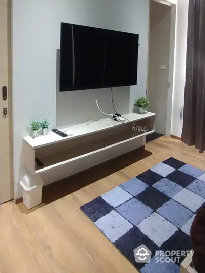 Modern minimalist living room with sleek wall-mounted TV unit, cozy checkered rug, and subtle decorative plants enhancing the homely ambiance.