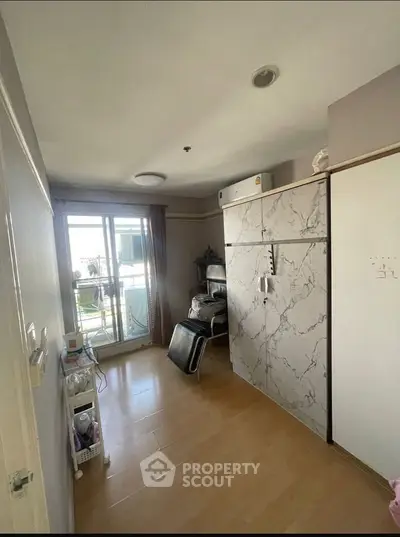 Cozy bedroom with large window and balcony access, featuring modern decor and ample natural light.