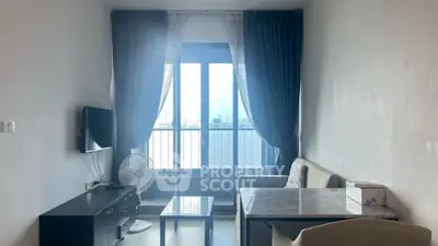 Bright living room with large window and modern furniture, offering a stunning city view.