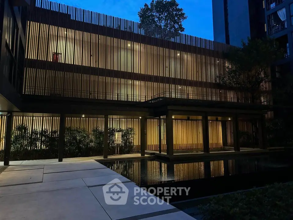 Modern architectural building with elegant lighting and serene water feature at dusk.