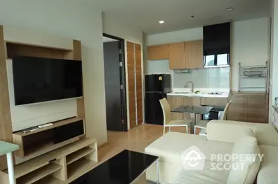 Modern living room with open kitchen, featuring sleek furniture and contemporary design.