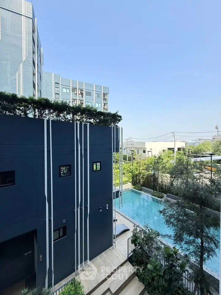 Modern apartment building with pool and lush greenery, offering a serene urban oasis.
