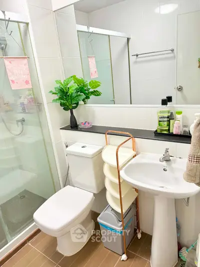 Modern bathroom with shower, toilet, and sink, featuring sleek design and bright decor.