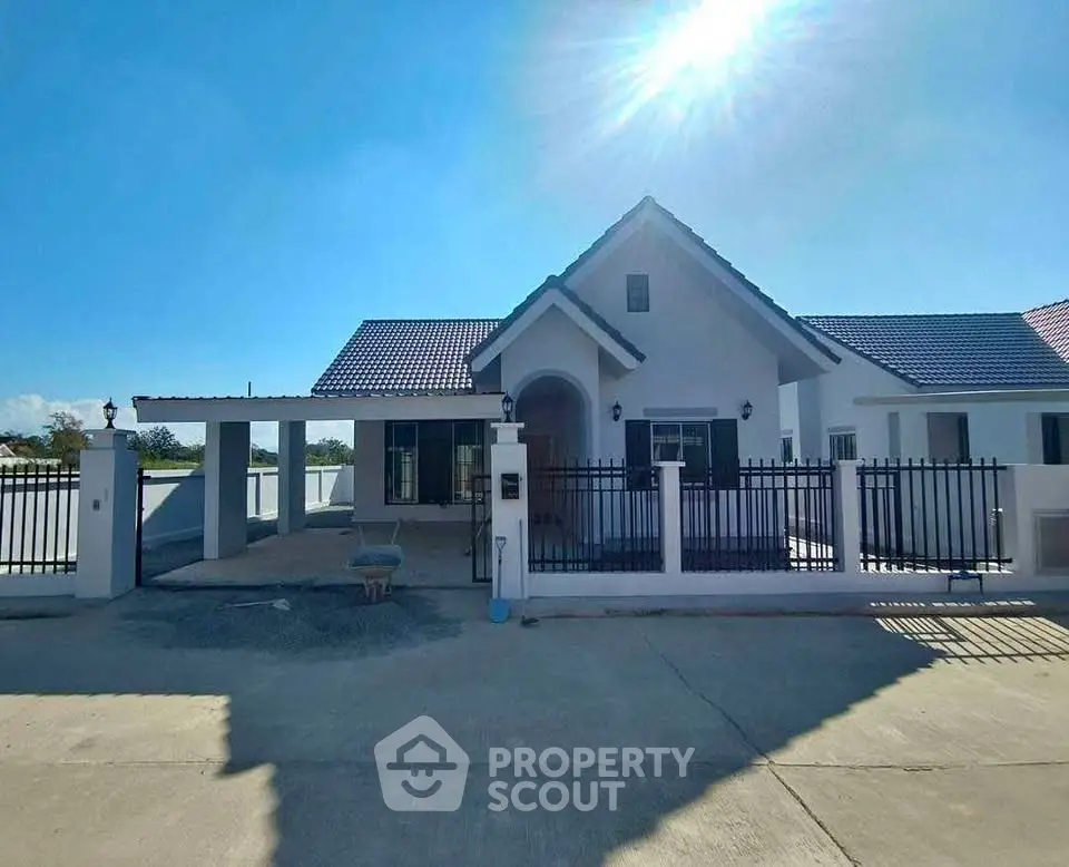 Charming single-story house with modern design and spacious driveway under clear blue sky.