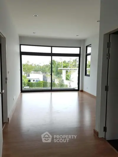 Spacious room with large windows offering a serene garden view, perfect for a bright and airy living space.