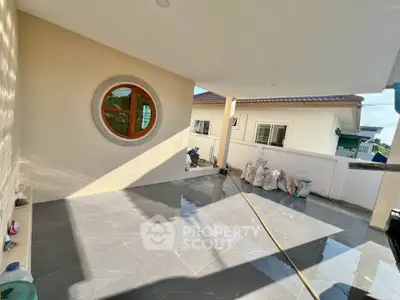 Spacious covered balcony with modern design and unique circular window.